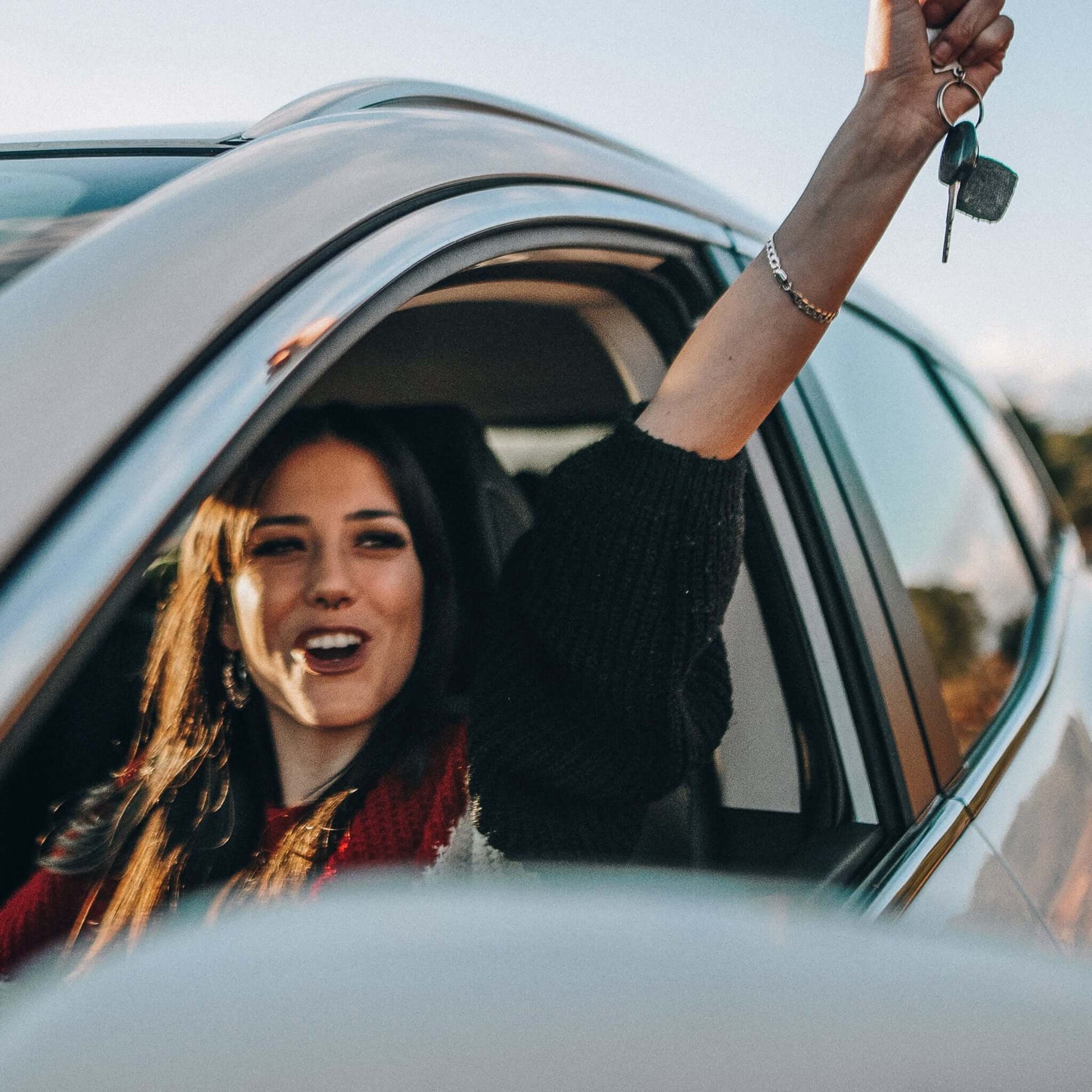 Перевод водительского удостоверения: Молодая женщина сидит за рулем и радуется тому, что у нее есть водительские права